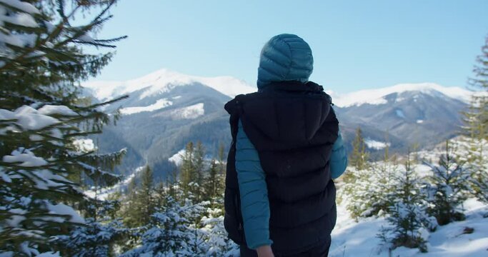 a child in a hiking jacket with a hood walks in the mountains in winter against the background of snow-capped peaks. Alps. a woman walks with a white dog in the mountains. tracking from the first pers