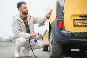 Man holding power connector for electric car