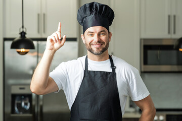 Idea for food. Portrait of chef man in a chef cap in the kitchen. Man wearing apron and chefs...