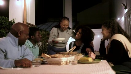 Family dinner: Happy African American people dining together at home terrace outdoors - Healthy food lifestyle