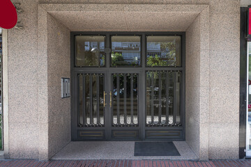 Access portal to a residential housing building with a black metal door with golden details and...