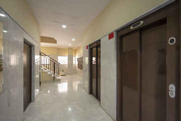 Access elevator to a residential building with brown metal doors and white marble tiles