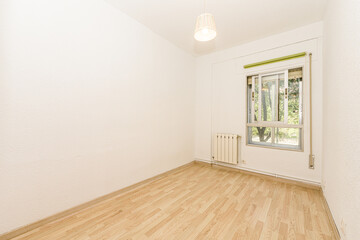 Empty room with laminate flooring with aluminum window overlooking a garden with trees