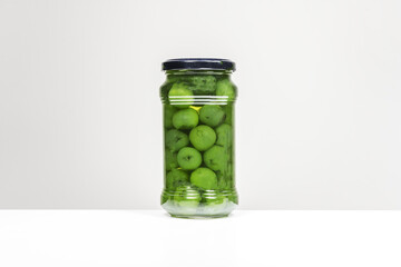 A glass jar with green sweet cherries