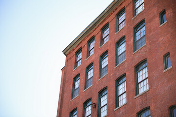 Fototapeta premium historic brick building structure with glass windows of urban apartment building old residential construction in boston downtown street with blue sky and business concept symbolizing monotonous work