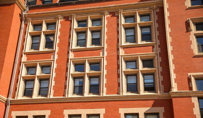 historic brick building structure with glass windows of urban apartment building old residential construction in boston downtown street with blue sky and business concept symbolizing monotonous work