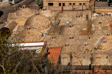domed underground Sulfer bathhouses using springs that Tibilis Georgia got its name from-looking down from Narikata with blurred weeds in foreground - obrazy, fototapety, plakaty