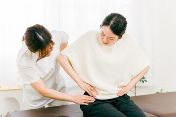 Obraz premium 整体院・整骨院に骨盤矯正きた患者と整体師・マッサージ師・セラピスト・医師の女性 