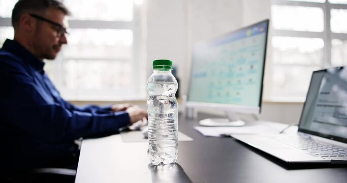 Water Bottle On Desk And Man In Background