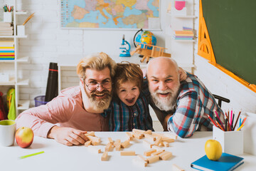Father and son playing in school class. Child hugging young father and elderly grandfather. Happy...