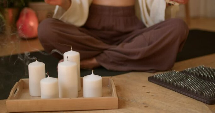 young woman sitting in lotus position and blowing out the candles,Aromatherapy Stress Relief, girl holding matches, has inished yoga practice. slow motion cropped closeup shot