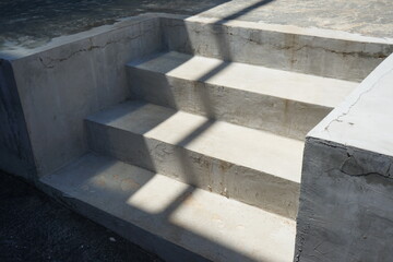 Gray concrete staircase in the city at the entrance to the building. Light and shadow. Summer. Day. Grunge.