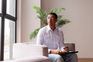 young African American psychologist in shirt and glasses sits in chair and listens, employee of...