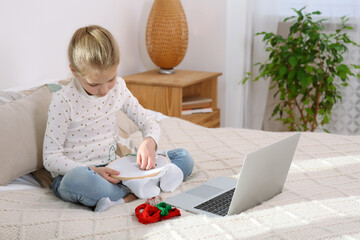 Little girl learning to embroider with online course at home. Space for text