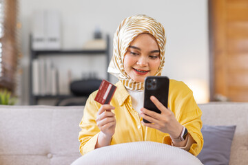 Easy payments. Smiling arabic woman or muslim woman in hijab in headscarf using phone and credit...
