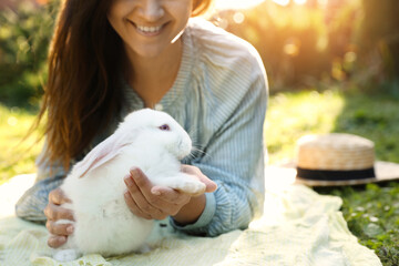 Happy woman with cute rabbit on green grass outdoors, closeup