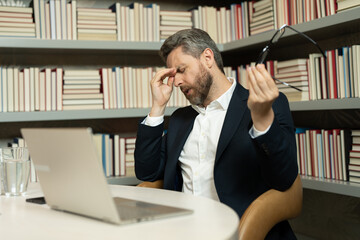 Fototapeta premium Tired man having a terrible headache. Exhausted man feeling unhealthy, upset about headache illness. Stressed middle-aged man having headache. Migraine and headache concept.