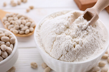 Fototapeta na wymiar Kidney bean flour and seeds on white wooden table, closeup