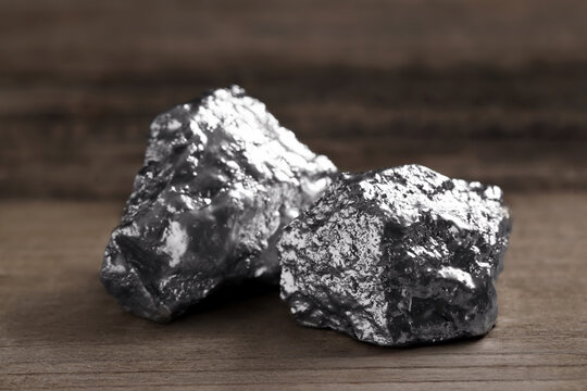 Two silver nuggets on wooden table, closeup