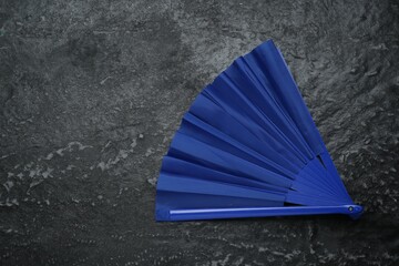 Bright blue hand fan on grey textured background, top view. Space for text