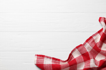 Red checkered tablecloth on wooden table, top view. Space for text