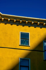 Sunstreak suburban city building with orange stucco cement exterior and decorative accent facade with windows and blue sky