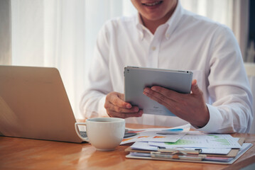 Businessman using smart digital tablet at office desk via wireless internet technology working online. Asian handsome man hold smart tablet use gadget check news. Freelance business person technology