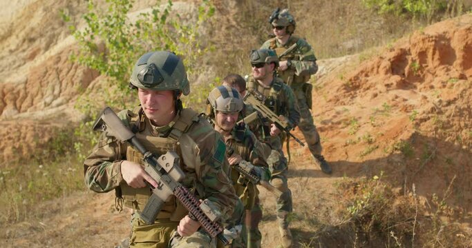 young people with weapon, in helmet, camouflages are standing on line, playing stike ball, slow motion