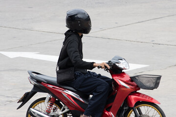 A man in black clothes and a helmet rides a motorcycle