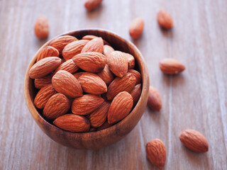 Organic almonds seed in wooden bowl over rustic wood background. Healthy food..