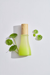 A jar with wooden cap decorated with gotu kola leaves against a white background. Cosmetic product branding mockup. Gotu kola (Centella asiatica) is good for skin