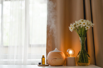 Aromatherapy concept. Aroma oil diffuser on the table against the window. Air freshener. Ultrasonic...