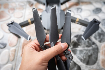 Someone holding a broken drone propeller. A damaged drone propeller affects performance mainly by causing vibration issues. - obrazy, fototapety, plakaty