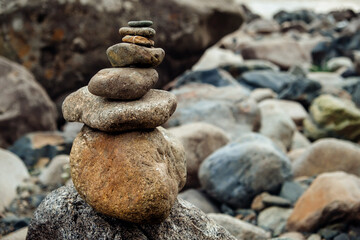 Fototapeta na wymiar Pyramid of stones in the mountains. Cairn making by tourists. Abstract rock construction.