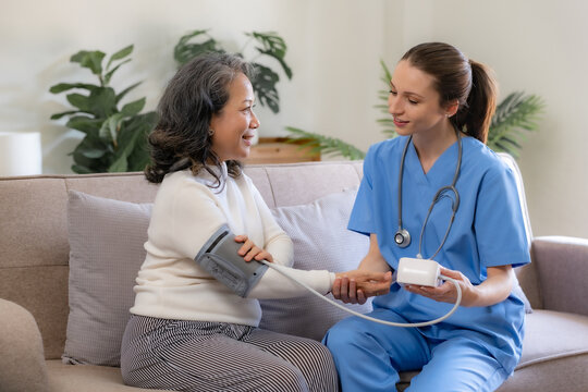 Female doctor check health and measures blood pressure of senior patient for initial examination at home.