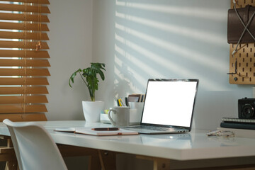 Working desk with laptop computer, retro camera, coffee cup and books on white table.