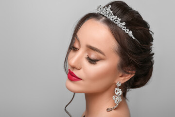 Beautiful young woman wearing luxurious tiara on light grey background. Space for text