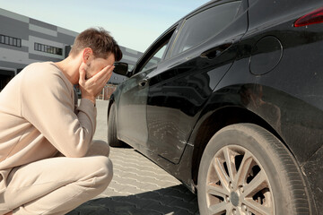 Stressed man near car with scratch outdoors