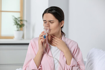 Sick young woman using nebulizer at home