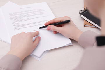 Woman signing document at wooden table, closeup