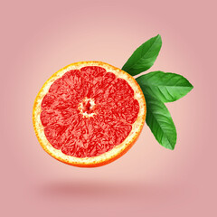 Cut fresh grapefruit and green leaves on dusty pink background