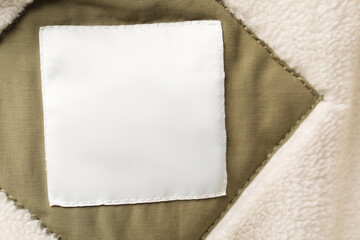 Clothing label on beautiful soft garment, top view
