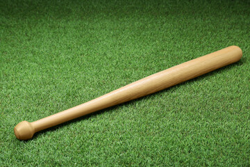 Fototapeta na wymiar Wooden baseball bat on green grass, above view. Sports equipment
