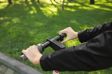 Man riding modern electric scooter in park, closeup