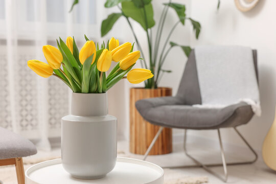Spring interior. Bouquet of beautiful yellow tulips on white table in living room, space for text