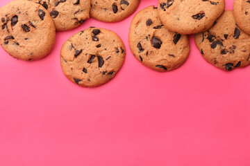 Many delicious chocolate chip cookies on pink background, flat lay. Space for text