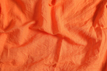Crumpled orange fabric as background, top view