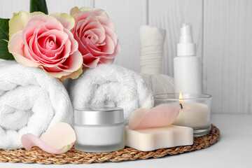 Fototapeta na wymiar Composition with different spa products, roses and candle on white table against wooden background