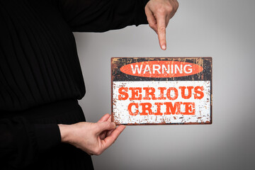 Serious Crime Concept. Warning sign with text on a white background in a woman's hand