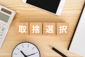 取捨選択と書かれたブロック、電卓、スマホ、ノート、時計